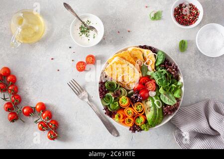 Ketogenic paleo Diät Mittagessen Schüssel. Halloumi Käse, Avocado Karotte Gurkensalat Blätter Stockfoto