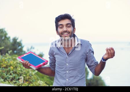 Verwirrt Schüler. Nahaufnahme Porträt verwirrt ahnungslos jungen Mann halten, zeigt Tablette Pad-Bildschirm, Arm heraus zu fragen, was ist Problem, wer kümmert sich so, was ich d Stockfoto