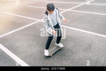 Teenager Skateboarder Junge mit einem Skateboard auf Asphalt Spielplatz macht Tricks. Jugend Generation Freizeit Ausgaben Konzept Bild. Stockfoto