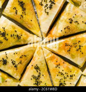 indische Samosa aus Phyllo mit würzigen Kartoffeln und Gemüse auf einem Backblech, fertig zum Backen im Ofen mit schwarzen Sesamsamen Stockfoto