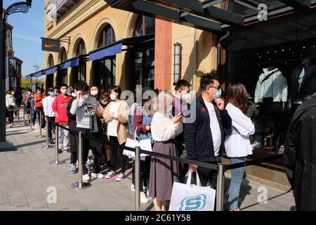 Menschenmenge, die eine Schutzmaske gegen Coronaviren trägt, muss sich vor dem NIKE Store anstellen und auf den Einkauf warten. Stockfoto