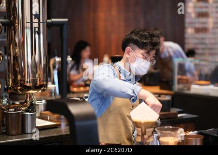 Nahaufnahme Angestellte trägt Gesichtsmaske, um covid-19 Coronavirus zu vermeiden, arbeiten im Café Stockfoto