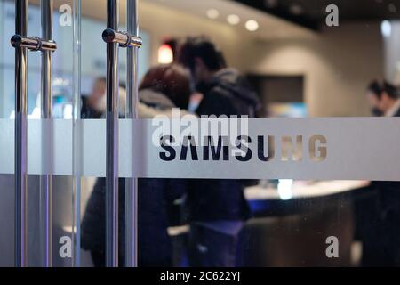 Nahaufnahme Samsungs Logo auf Glastür des Geschäfts. Verschwommener Kunde im Laden. Stockfoto