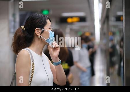 Nahaufnahme eine asiatische junge Frau in Gesichtsmaske, um Coronavirus zu verhindern, auf U-Bahn-Plattform stehen. Hintergrund verwischen Stockfoto