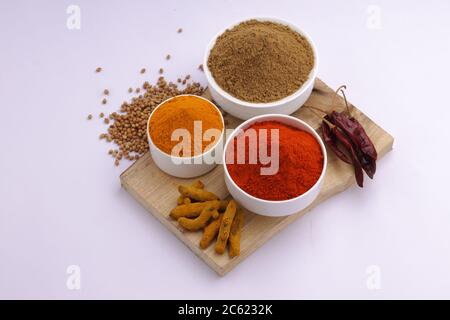 Indische Gewürze Chili, Kurkuma und Koriander sind die drei grundlegenden Gewürze für indische Curry oder Gerichte, in aweißen Schalen angeordnet Stockfoto