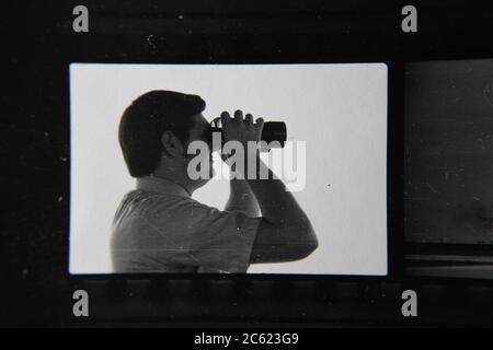 Feine 70er Jahre Vintage Kontaktdruck schwarz-weiß Fotografie eines Mannes durch sein Fernglas während der Arbeit schauen. Stockfoto