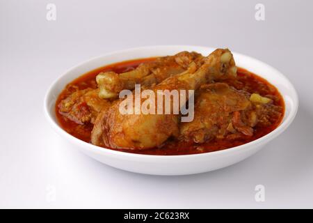 Chicken Curry oder Masala, würzige rötliche Huhn Masala Curry mit Gewürzen, Zwiebeln und Knoblauch in nordindischen Stil in einer weißen Keramikschale gemacht Stockfoto