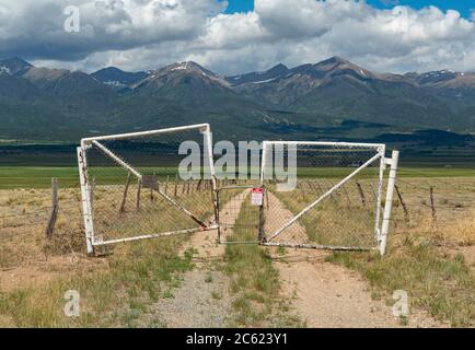 Altes verwittertes rostiges Metalltor mit felsigen Bergen, Colorado USA Stockfoto