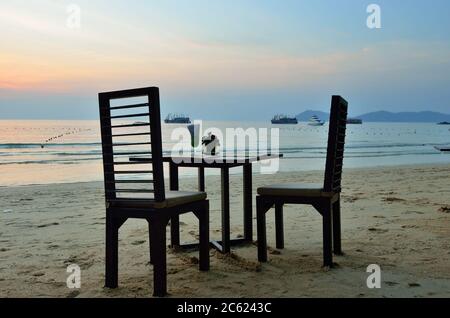 Strandcafé auf den Samet Inseln, Thailand. Stühle und Tisch am Sandstrand gegen Sonnenuntergang über dem Meer Stockfoto
