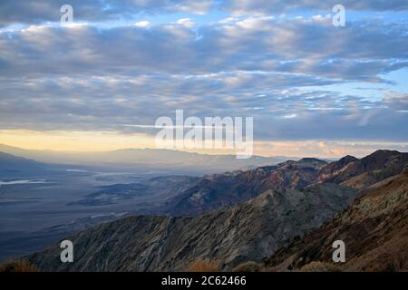 Sonnenuntergang in Dantes Blick über Death Valley, Kalifornien. Blick nach Norden in Richtung Furnace Creek. Die Sonne bricht durch die Wolken, als sie zu untergehen beginnt. Stockfoto