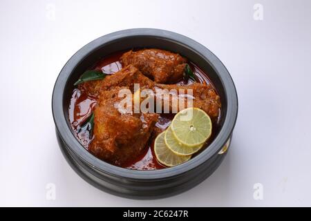 Hammelcurry oder Lamm Curry, würzige und köstliche Gericht garniert mit Curryblättern und Zitronenscheiben in einem schwarzen Gefäß mit weißer Textur oder Hintergrund, ein Stockfoto