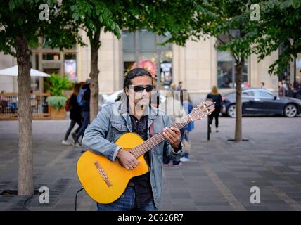 Feine akustische Gitarrist spielt für Mitglieder der Öffentlichkeit auf belebten Straßen Montreal im Herbst. Stockfoto