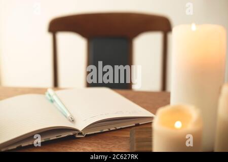 Notizbuch für Tagebucheinträge auf dem Tisch mit Kerzen. Stockfoto