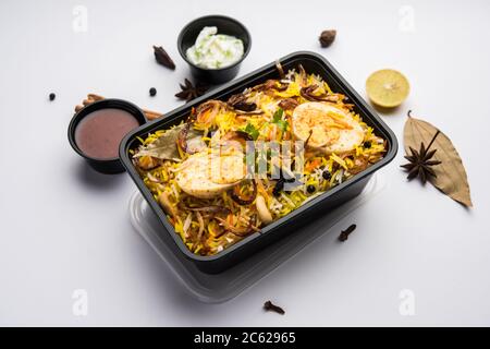 Restaurant Stil Ei Biryani oder Anda Pulao verpackt für die Hauslieferung in Plastikbox oder Container mit Raita und Salan Stockfoto