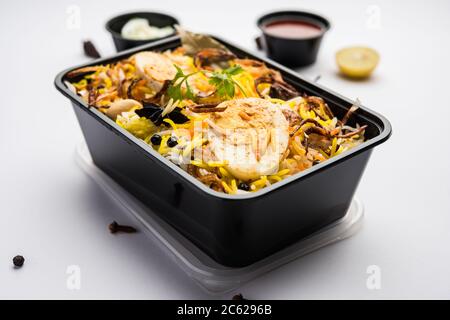 Restaurant Stil Ei Biryani oder Anda Pulao verpackt für die Hauslieferung in Plastikbox oder Container mit Raita und Salan Stockfoto