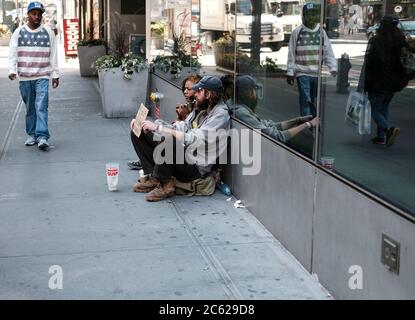 Junge obdachlose Paar sah auf der Suche nach Wohltätigkeitsorganisationen von Passanten in Zentral-New York mit einem Mitglied der Öffentlichkeit vorbei. Stockfoto