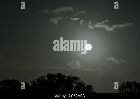 Landschaftlich schöner Blick auf den Vollmond mit Wolken. Planet Jupiter mit Monden ist direkt über dem großen hellen Mond sichtbar. Stockfoto