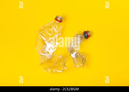 Zwei gebrauchte Plastikflaschen auf gelbem Hintergrund. Das Konzept der Verschmutzung des Planeten und der Ozeane mit Plastikmüll. Stockfoto