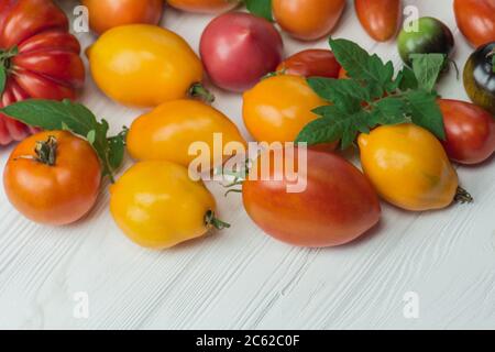 Die Ernte von verschiedenen Tomaten. Sorte reif natürlich Bio lecker verschiedene Tomaten. Tomaten auf Holzhintergrund. Stockfoto