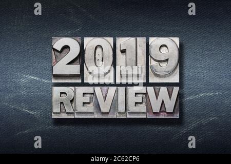 2019 Review Phrase aus Metallic-Buchdruck auf dunklem Jeans-Hintergrund Stockfoto