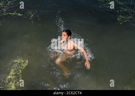 Srinagar, Indien. Juli 2020. Ein Kind schwimmt in Dal See während eines heißen Sommertages in Srinagar. Kredit: SOPA Images Limited/Alamy Live Nachrichten Stockfoto