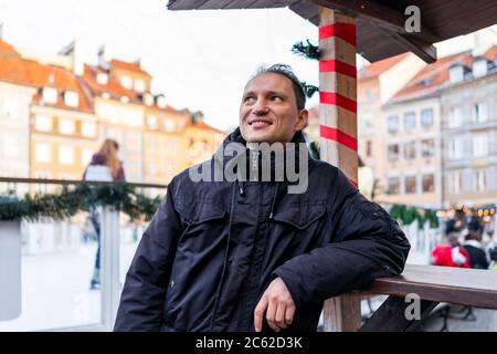 Junge glückliche Tourist Mann in Warschau, Polen Altstadt Marktplatz rynek in Warszawa Weihnachtsschmuck mit Menschen Schlittschuh in Eisbahn Stockfoto