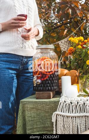 Eine Frau in einem Pullover hält ein Glas Wein aus einem transparenten Spender. Stockfoto