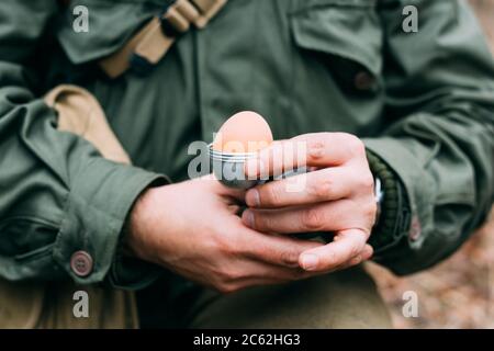 Soldat der USA Infanterie des Zweiten Weltkriegs hält Eierhalter in den Händen während des Frühstücks. Stockfoto