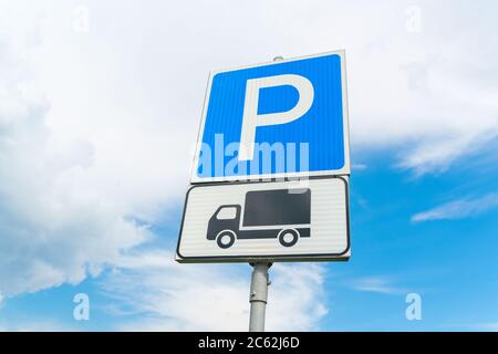 LKW-Parkplatz Schild gegen den blauen Himmel. Blaues Parkschild. Schwarzer LKW auf weißem Schild. Hochwertige Fotos Stockfoto