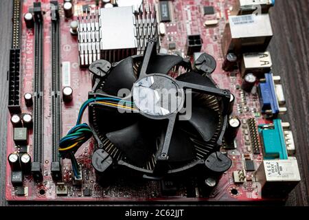 Ukraine - 25. April 2020: Nahaufnahme des Computer-Motherboards mit CPU-Coller auf braunem Hintergrund. Hardwarekomponenten, Hintergrund Stockfoto