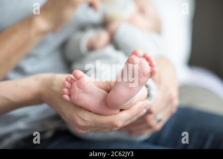 Nahaufnahme von Babyfüßen, die von den Händen der Mutter gehalten werden Stockfoto