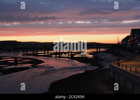 Der Adur-Fluss ist Weg zum Meer durch Shoreham by Sea bei einem bunten Sonnenuntergang und Reflexion Stockfoto