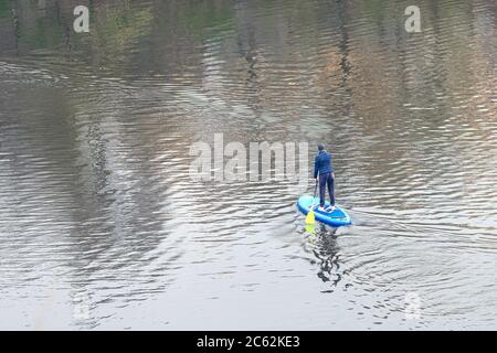 Draufsicht auf trainierte Frau, die auf dem Stand-up-Paddle-Board steht und auf dem ruhigen Wasser des Flusses läuft. Mädchen paddeln auf SUP im Fluss. Stockfoto