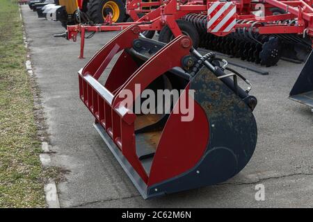 Ein großer roter Eimer für Landmaschinen liegt auf dem Boden. Nahaufnahme. Stockfoto