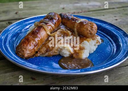 Vegane Bangers & Mash mit Fleischwürsten, Soße, Kartoffelpüree in einer Camping-Emaille-Platte, Abendessen Stockfoto