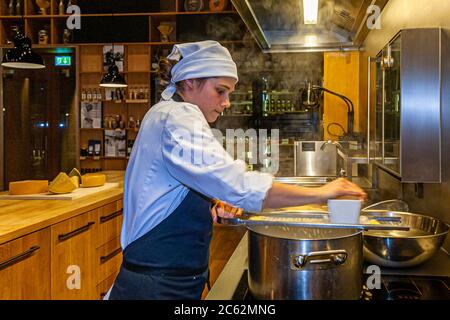 Der Knöpfler in Aktion. Kässpätzler werden auch Käsknöpfle genannt. Frische Pasta mit Reibe - typisch österreichische Käsepasta - Teig fällt in kochendes Wasser Stockfoto