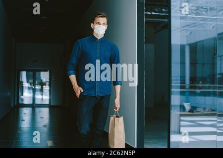 Junger Mann in einer Schutzmaske, der eine Stadtstraße entlang läuft Stockfoto