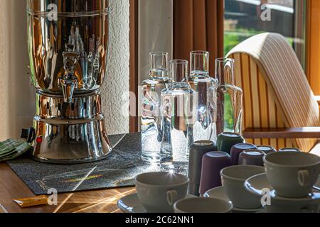 Elmauer Wasser - Bergquellwasser -drei Flaschen Quellwasser stehen vor einem Fenster mit Bergen im Hintergrund. Elmau Wasser - ein wissenschaftlich gesichertes Trinkwasser. Das beste Bergquellwasser fließt im Schiff aus allen Trinkwasserarmaturen. Zuvor durchläuft sie den Ellmauer Licht- und Energiegenerator, um Energie- und Lichtdefizite in den Wassermolekülen auszugleichen Stockfoto