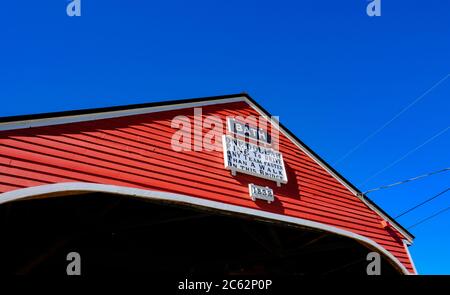 Klassische Holzbaubrücke mit architektonischen Details, die vor einem klaren blauen Herbsthimmel gesetzt sind. Stockfoto