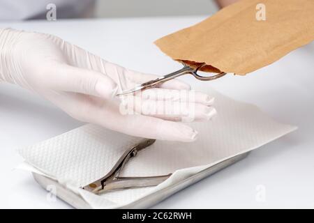 Manikuristen Hände nehmen Maniküre Werkzeuge aus Handwerk Umschlag vor Maniküre Verfahren durch den weißen Tisch Stockfoto