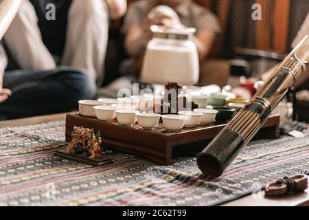 Tee-Party im Stil von Boho, Hippie. Tee-Tassen auf einem speziellen Holz-Couchtisch. Zubereitung von Masala-Tee. Ein Didgeridoo. Tee wird auf der Tanne zubereitet Stockfoto