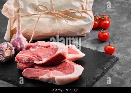 Zwei Stücke Schweinefleisch auf einem Schieferteller auf einem grauen Hintergrund. Kopierraum, Foto für Lebensmittelgeschäfte Stockfoto