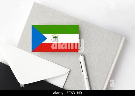 Äquatorialguinea Flagge auf minimalistischem Buchstaben Hintergrund. Nationaler Einladungsumschlag mit weißem Stift und Notizbuch. Kommunikationskonzept. Stockfoto