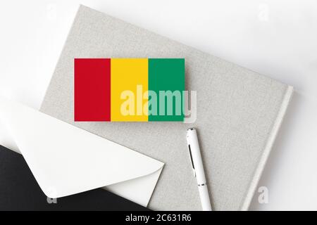 Guinea Bissau Flagge auf minimalistischem Buchstaben Hintergrund. Nationaler Einladungsumschlag mit weißem Stift und Notizbuch. Kommunikationskonzept. Stockfoto