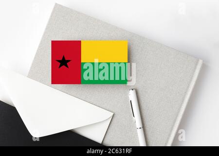 Guinea Flagge auf minimalistischen Buchstaben Hintergrund. Nationaler Einladungsumschlag mit weißem Stift und Notizbuch. Kommunikationskonzept. Stockfoto