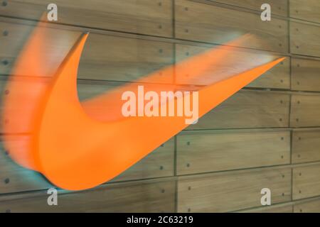 Moskau, Russland - 11. April 2018: Orangefarbenes Nike Logo auf braunem Wandhintergrund im Einkaufszentrum 'Okhotniy Ryad' Stockfoto