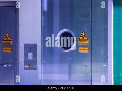 Riems, Deutschland. Juli 2020. Das Warnschild für Biogefährdung hängt an einer speziellen Schleusentür vor einem Labor der Sicherheitsstufe 4 in einem Laborgebäude des Friedrich-Loeffler-Instituts auf der Insel Riems. Die Bundesforschungsanstalt für Tiergesundheit hat die Aufgabe, einerseits die Gesundheit von lebensmittelproduzierenden Tieren zu erhalten und andererseits Menschen vor Zoonosen zu schützen. Das derzeit dringlichste Forschungsprojekt sind Tierversuche zur Erforschung des neuartigen Coronavirus. Quelle: Jens Büttner/dpa-Zentralbild/ZB/dpa/Alamy Live News Stockfoto