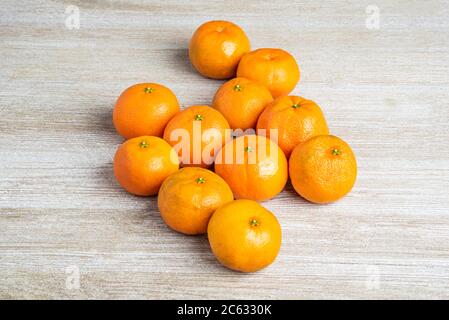 Eine Gruppe frischer Orangen kunstvoll auf einer weiß bemalten strukturierten Holztafel angeordnet. Stockfoto