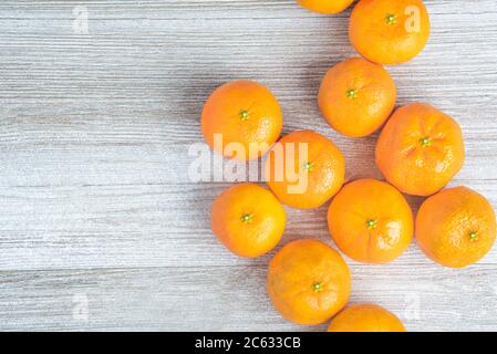 Eine Gruppe frischer Orangen kunstvoll auf einer weiß bemalten strukturierten Holztafel angeordnet. Stockfoto