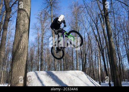 mtb-Fahrer macht Trick auf Dirt Springen im Winter. Radfahrer tun Sprungbrett Stunt Stockfoto